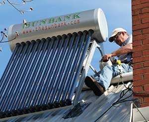 solar water heater being installed on a steep metal roof