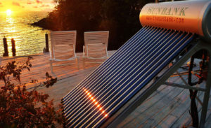 stand alone instllation of beautiful residential solar water heater ground mount installed on a deck in florida with water, sunset, and deck chairs behind it