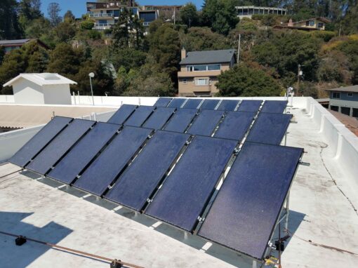 Photo of an array of flat plate solar water heater collectors on a flat roof of a multifamily commercial building